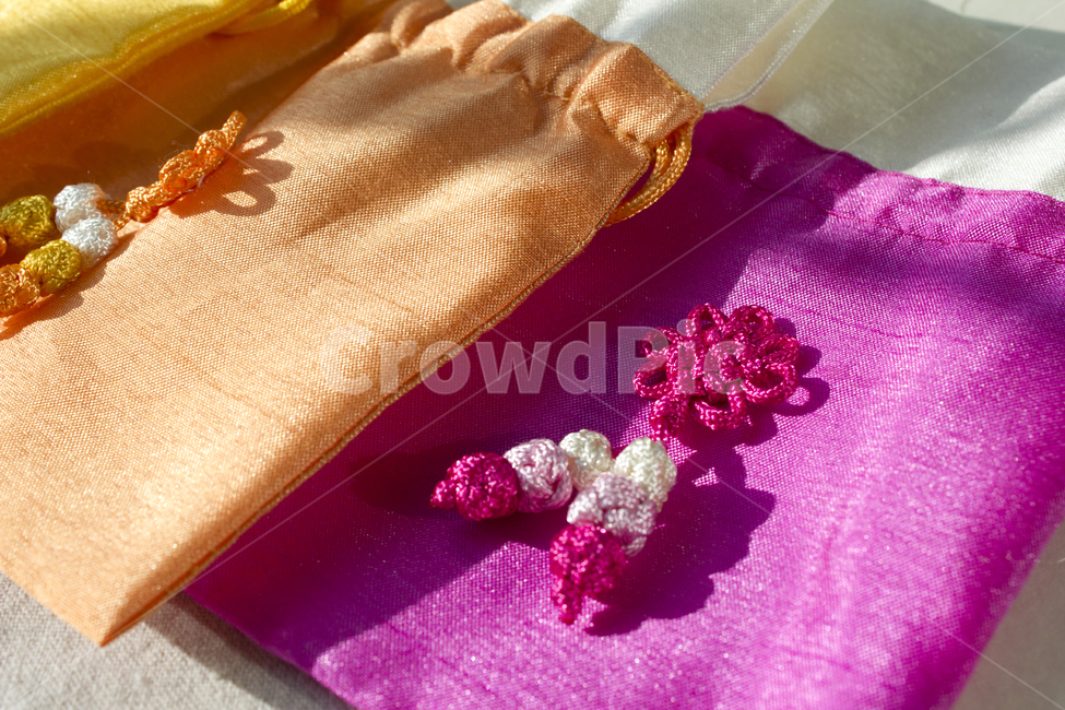 주머니,복주머니,아시아,동양,패브릭,공예품,명절,새해,설날,설,클로즈업,한국,전통,문화,한지,종이,한국문화,선물,사물,정물,소품,생활용품,생활소품,흰배경,끈,리본,매듭,오렌지색,주황색,핑크색,자주색,분홍색,실크