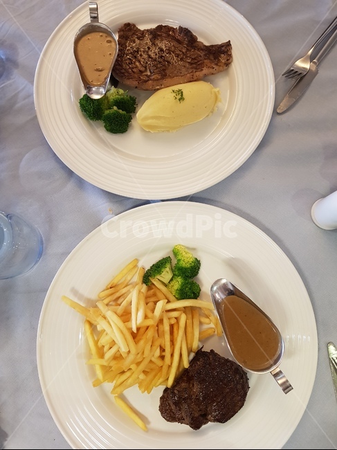스테이크,소고기,소고기스테이크,steak,beefstake,감자튀김,감자,브로콜리,양식,식사,음식,두접시,테이블,소스,프렌치프라이,고급,레스토랑,분위기,fork,포크,cutlery,나이프,knife