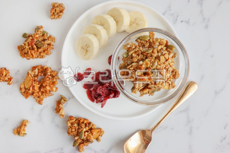 Nuts,granola,cereal,banana,oatmeal,sunflower seeds,cranberries,spoon,brunch