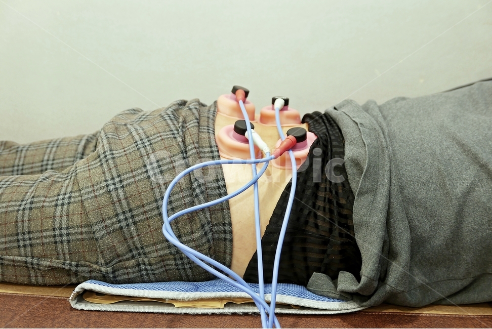 치료기,물리치료기,병원,저주파,물리치료,치료기구,기구,치료,고통,통증,호스,흡착,압박,전기,압력,실내,침대,사람,환자,여자,분홍색,하늘색,검정색,황토색,허리,찜질팩,한의원,의원,외과,통증클리닉,사람,인물,인간,human,person,건강,헬스웨어,헬스케어,healthware,health care,의료,의학,병원,medical,hospital,clinic