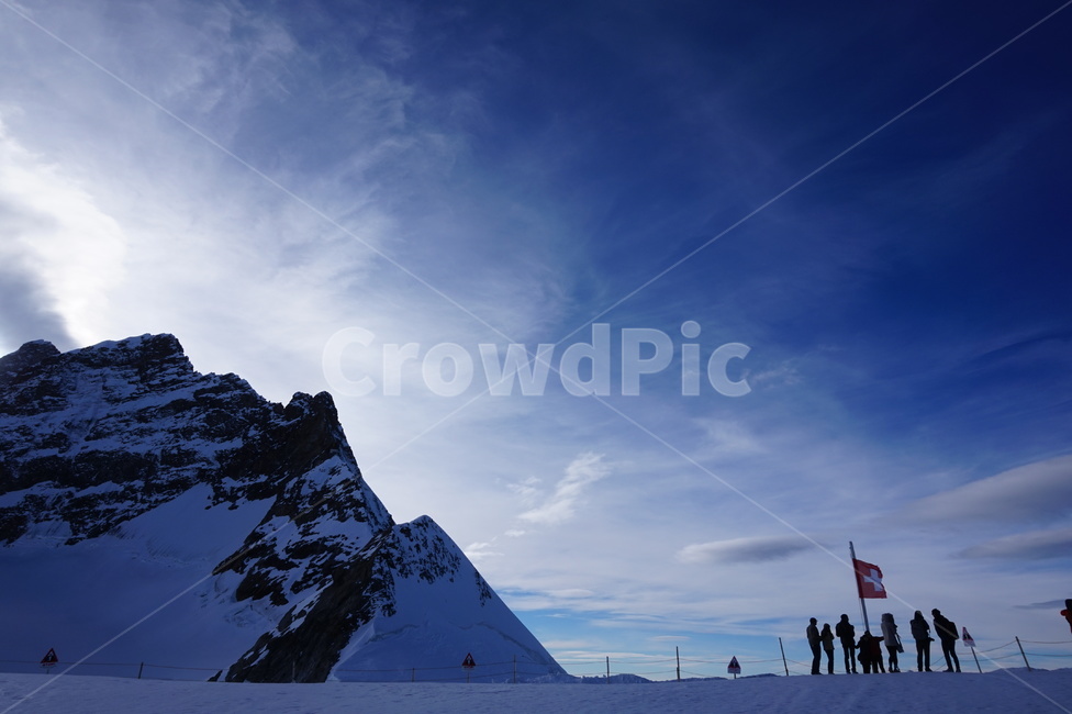 mountain peak,flag,Jungfrau,tourism,ice,summit,Jungfrau summit,cloud,tourist,pointed mountain,snowcapped mountain,flagpole,human,sky,nature,Switzerland,outdoors,snow,person