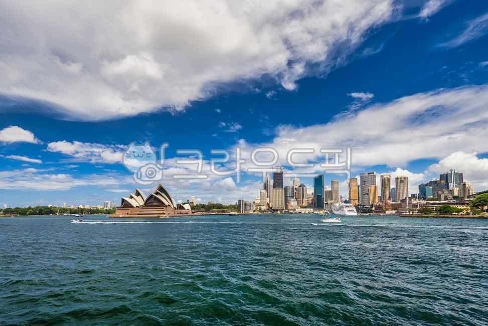 ship,passenger ship,famous place,trees,building,weather,cityscape,bay,skyscrapers,landmark,sunny,sky,development,metropolis,tourist destination,skyscraper,economy,water,operahouse,port,cruise,waterfront,Sydney,opera house,city,clouds,scenery,sun,sea,summe