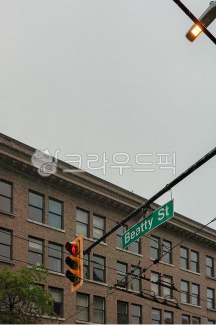 red light,traffic light,street,building,window,brick,sign,wire,pole,rain,grey sky,intersection,stop,streetlight,vancouver,canada,city,window,road,apartment,weather,outside,exterior wall,house