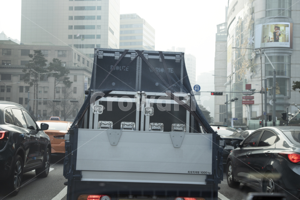 도로,박스,적재함,트럭,정차,신호등,빨간등,사거리,자가용,미등,끈,그물망,알루미늄,적재,튼튼한,네모,상자,로프,바,화물차,화물,배달,도심,쌓은,손잡이,승용차,택시,간판,미세먼지,차선,아스팔트,교통,산업,교통,교통수단,traffic,transportation