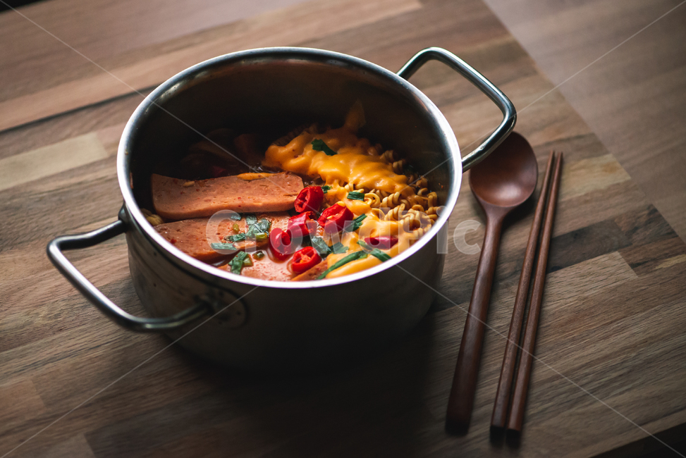 soup,wooden table,top view,Budaejjigae,Budae stew ramen,Spicy stew,chopsticks,Cheese bag stew,jjigae,spicy,cheese,spoon and chopsticks,ramen,Spoon,Haejangjjigae,spam,budaejjigae