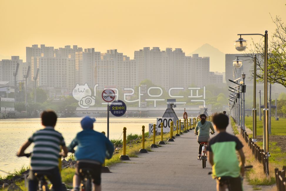 Life sports,information board,bicycle,road sign,riding,bike,vehicle,Street lamp,trail,human,traffic,Apartment village,Dusk,Cardiovascular exercise,transportation,lakeside,outdoors,person,background,sunset,road name,nightfall