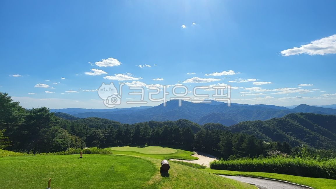 sky,green,golf course,nature,clear sky,mountain,blue,field,outdoors,sunny sky