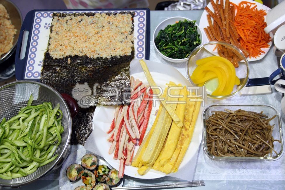 crab meat,spinach,Gimbap,egg,cucumber,seaweed,pickled radish,sausage,cutting board,burdock,carrot